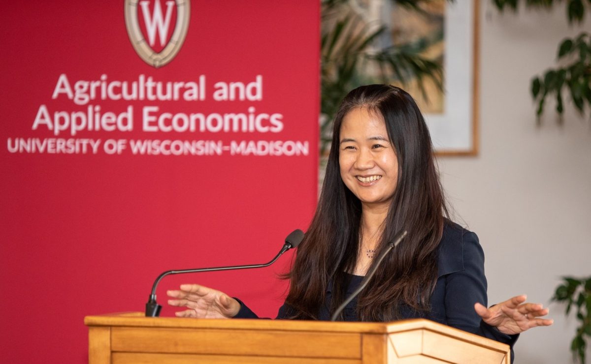 Guanming Shi standing at a podium in front of a banner saying Agricultural & Applied Economics