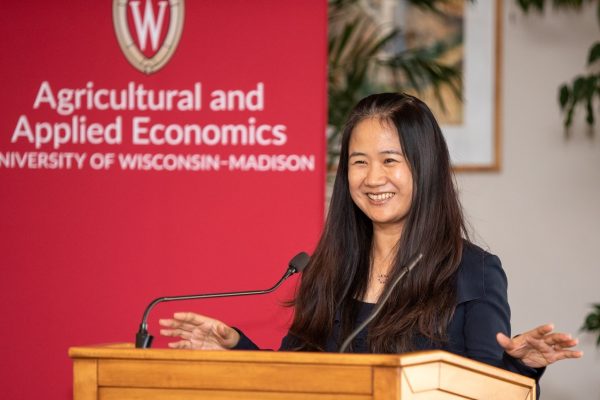 Guanming Shi standing at a podium in front of a banner saying Agricultural & Applied Economics
